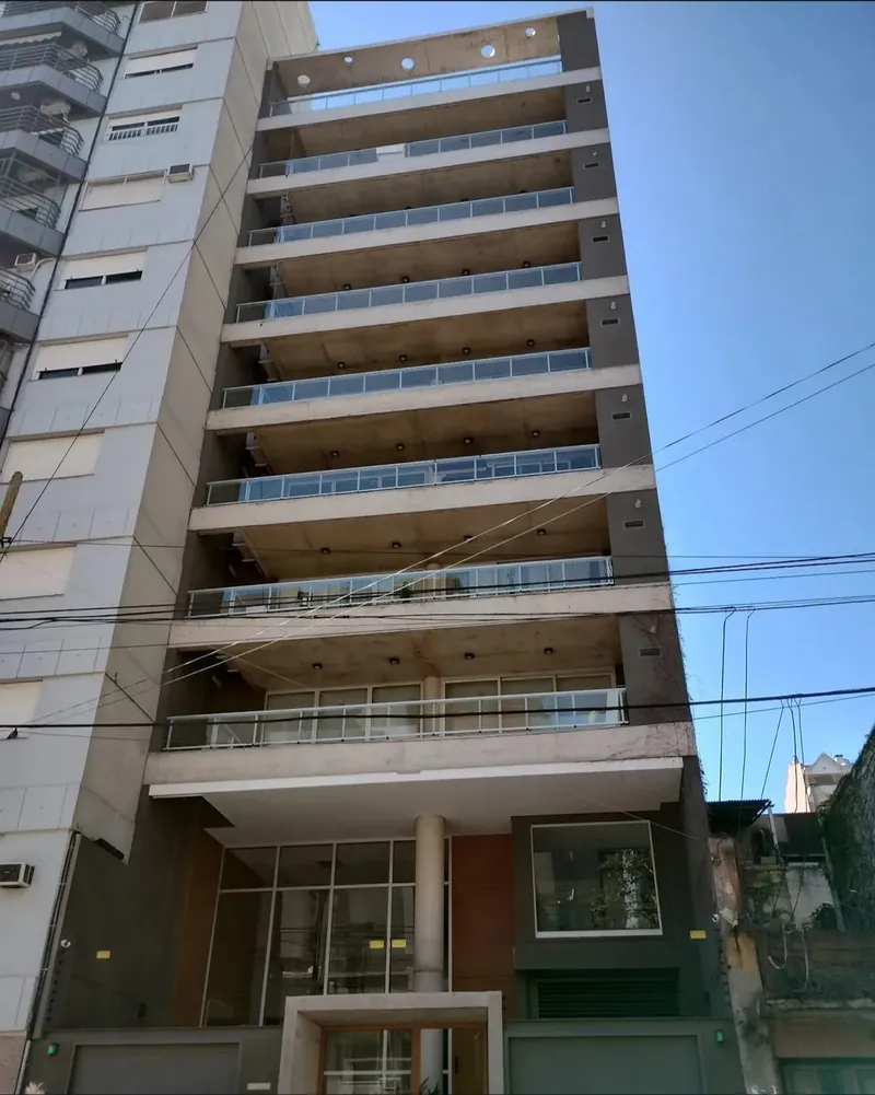 Edificio de viviendas con balcones en voladizo y losas de hormigón a la vista en Lanús